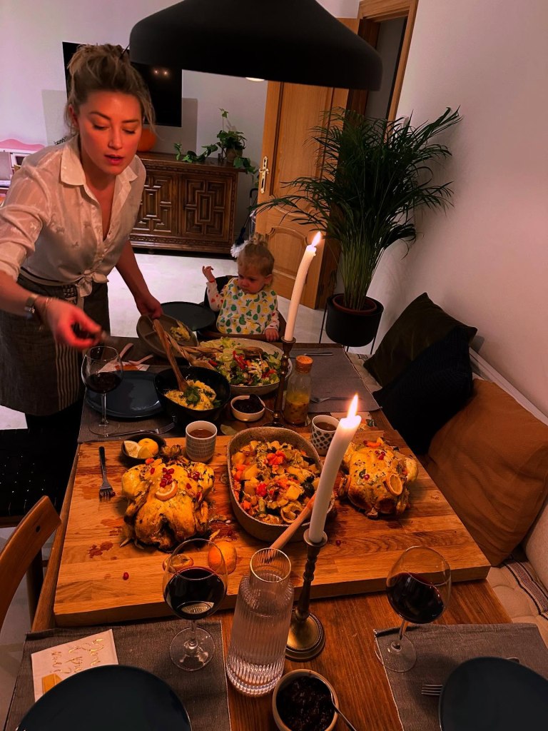 Amber Heard serving Thanksgiving dinner with a baby in a high chair in the background.