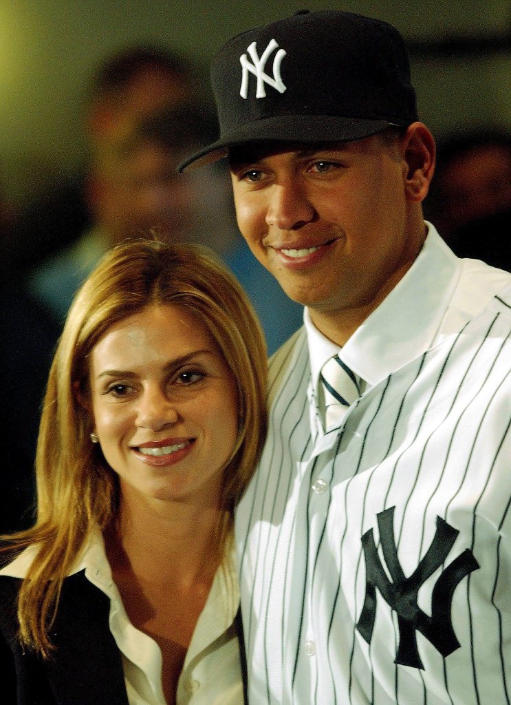 Alex Rodriguez in a Yankees uniform standing with then-wife Cynthia Scurtis at a press conference.