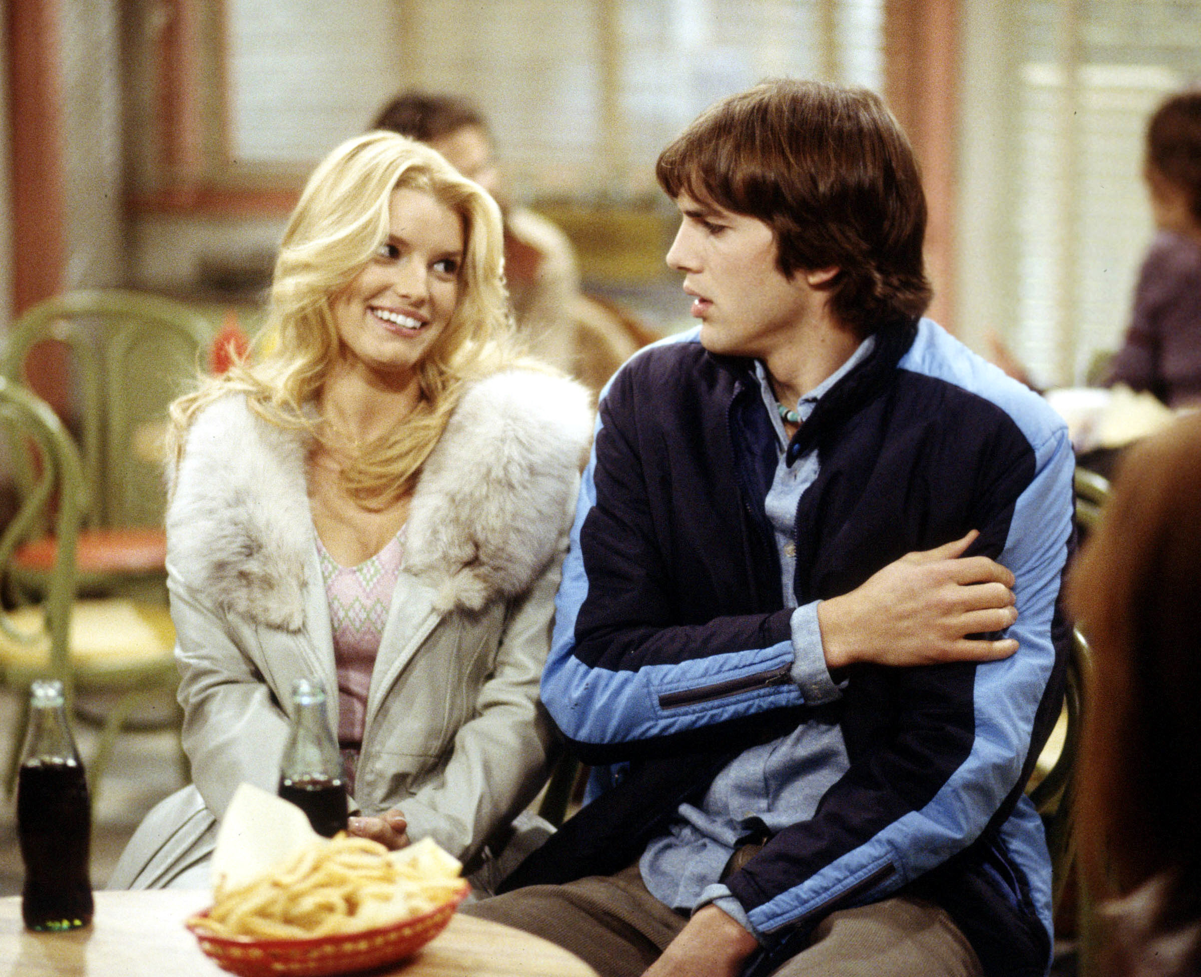Jessica Simpson and Ashton Kutcher sitting at a restaurant booth with sodas and french fries.