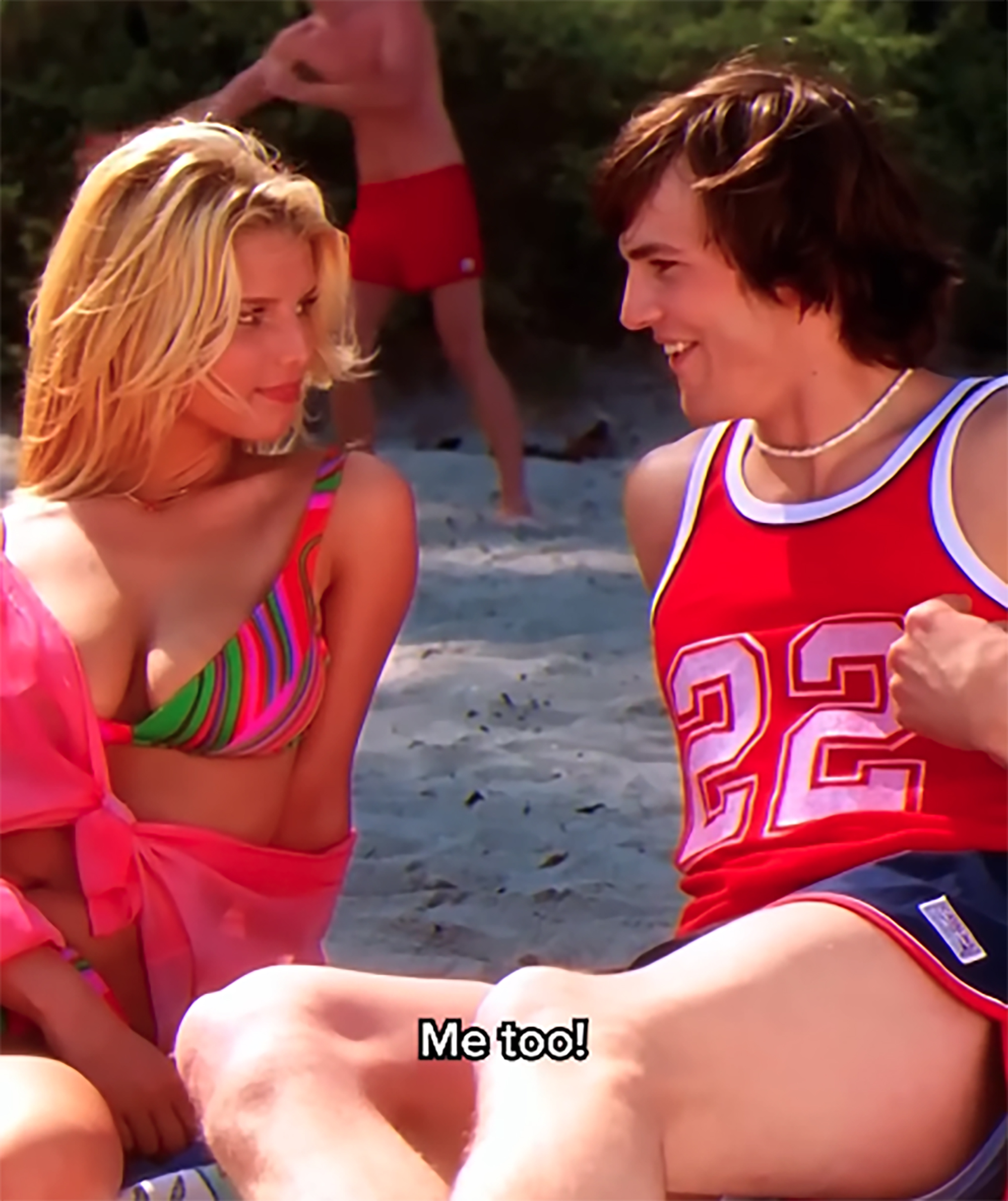 Jessica Simpson in a bikini and Ashton Kutcher in a red jersey on a beach in That '70s Show.