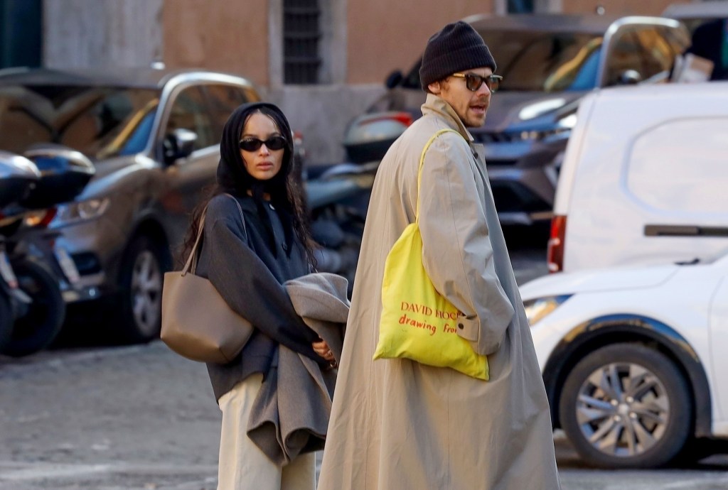 Styles in a beige trench with a yellow tote walks beside Kravitz in a gray peacoat and navy cardigan in Rome.