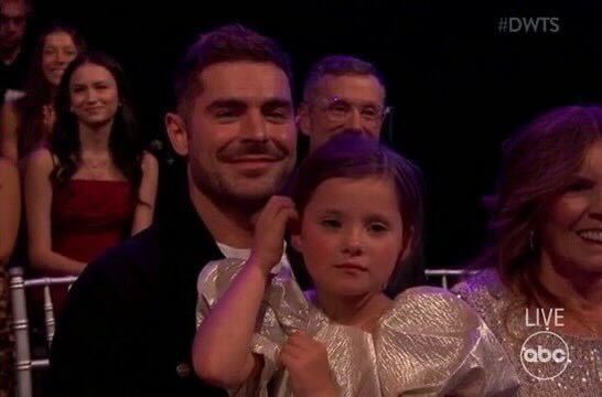 Zac Efron sits front row at Dancing With the Stars with his 5-year-old sister Olivia on his lap.