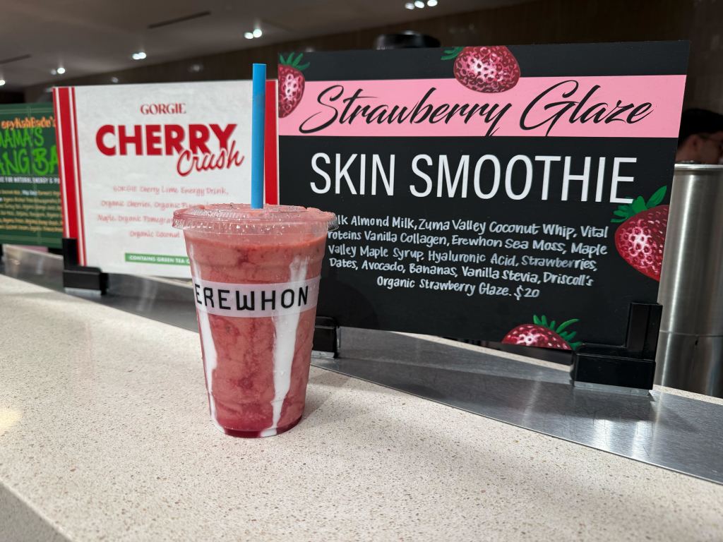 Erewhon Strawberry Glaze Skin Smoothie in a clear cup with pink-and-white layers.