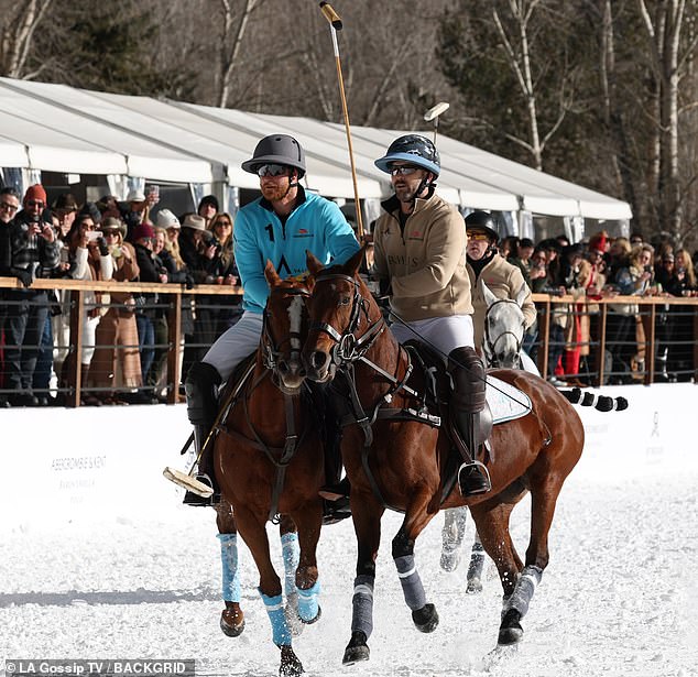 Prince Harry competes in the World Snow Polo Championships in Aspen wearing a vibrant blue pullover, white trousers, black helmet and sunglasses.