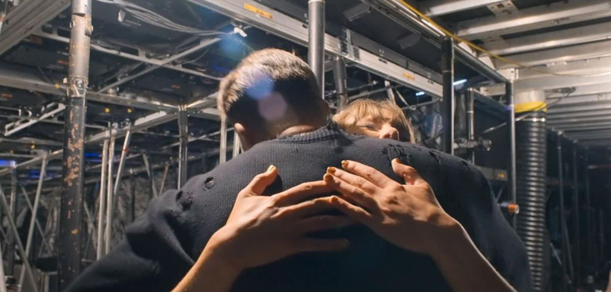 Taylor Swift and Travis Kelce share a backstage hug and kiss during the Eras Tour, as seen in the End of an Era docuseries.
