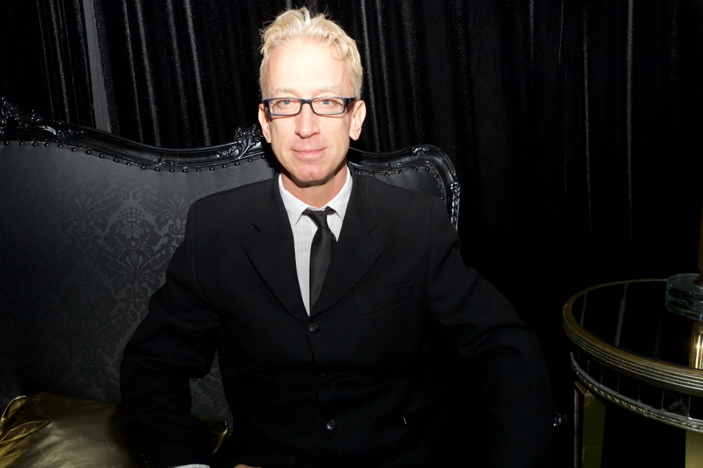 Andy Dick seated in an ornate black chair at an event.