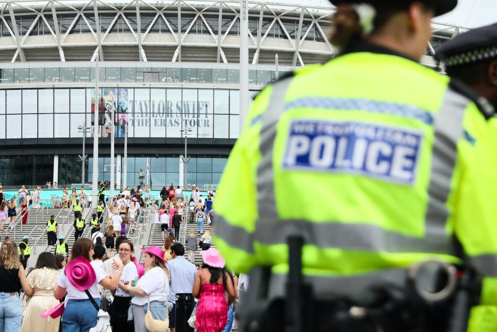 Police in high-visibility vests as fans enter Wembley Stadium for Taylor Swift's Eras Tour.