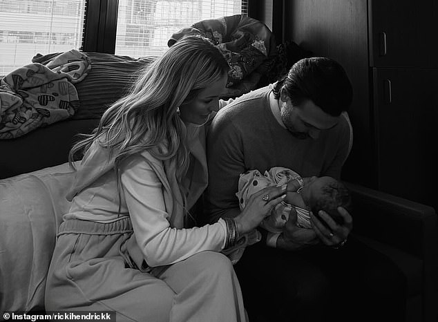 Tyler Johnson holds the newborn as Emily Maynard places a hand on the baby's arm in the hospital
