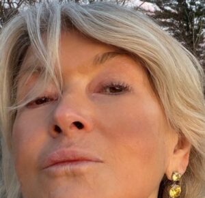 Close-up of Martha Stewart looking at the camera, wearing blonde hair, and two yellow gemstone earrings.