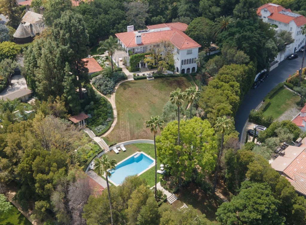 Aerial view of Angelina Jolie's Hollywood estate with a large white mansion, extensive gardens, and a swimming pool.