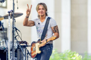 Keith Urban performing on NBC's Today show at Rockefeller Plaza, holding up a peace sign.