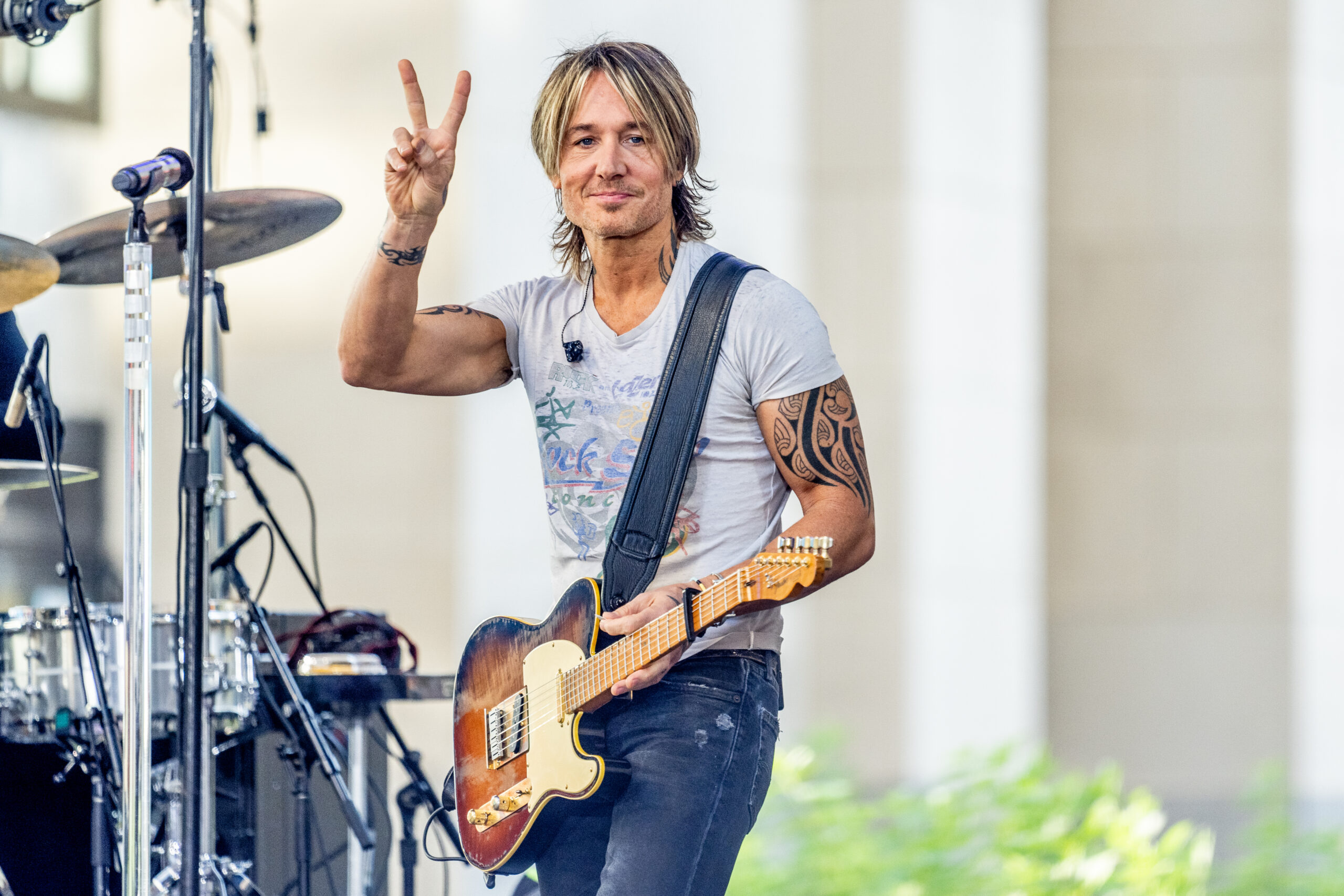 Keith Urban performing on NBC's Today show at Rockefeller Plaza, holding up a peace sign.