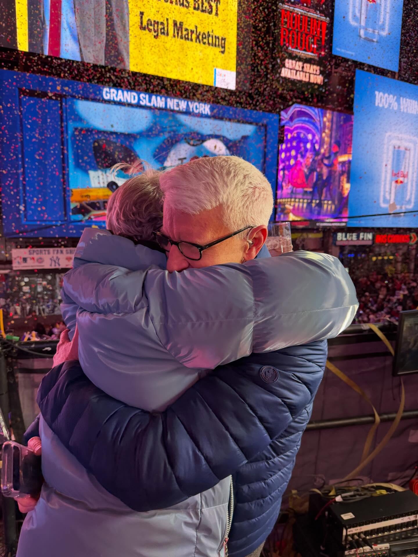 Anderson Cooper hugs Andy Cohen amid confetti during CNN's Times Square New Year's Eve broadcast.