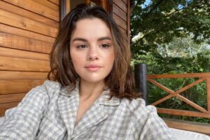 Selena Gomez smiles in a makeup-free Instagram Stories selfie, wearing a loose white tank top.