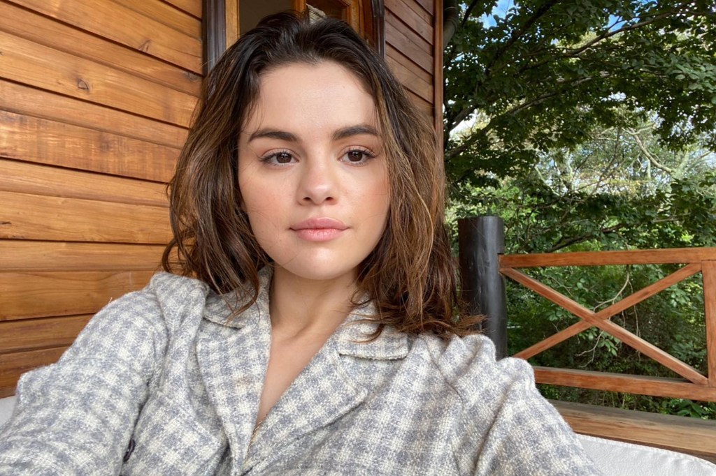 Selena Gomez smiles in a makeup-free Instagram Stories selfie, wearing a loose white tank top.