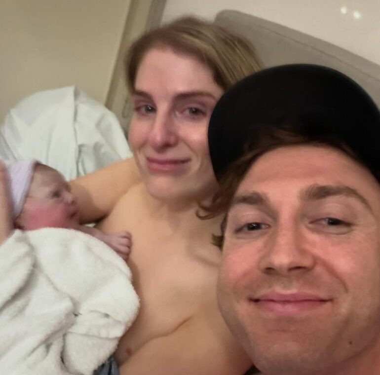 Meghan Trainor and her husband pose with their newborn baby.