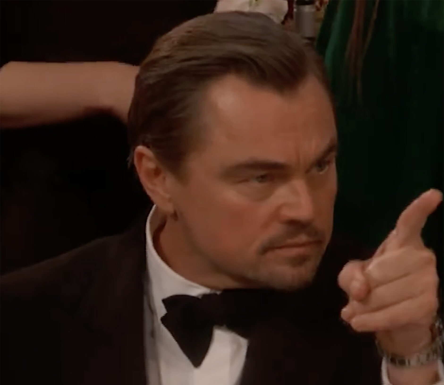 Leonardo DiCaprio pointing a finger while seated at an event.