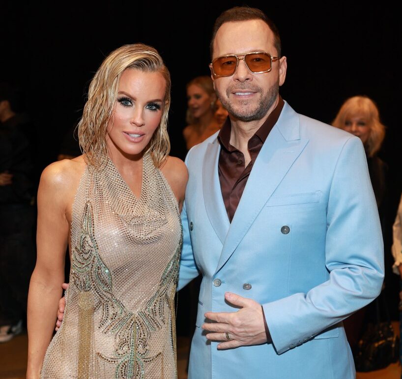 Jenny McCarthy in a sheer embellished gown and Donnie Wahlberg in a light blue suit and orange sunglasses at the 2025 iHeartRadio Music Awards.