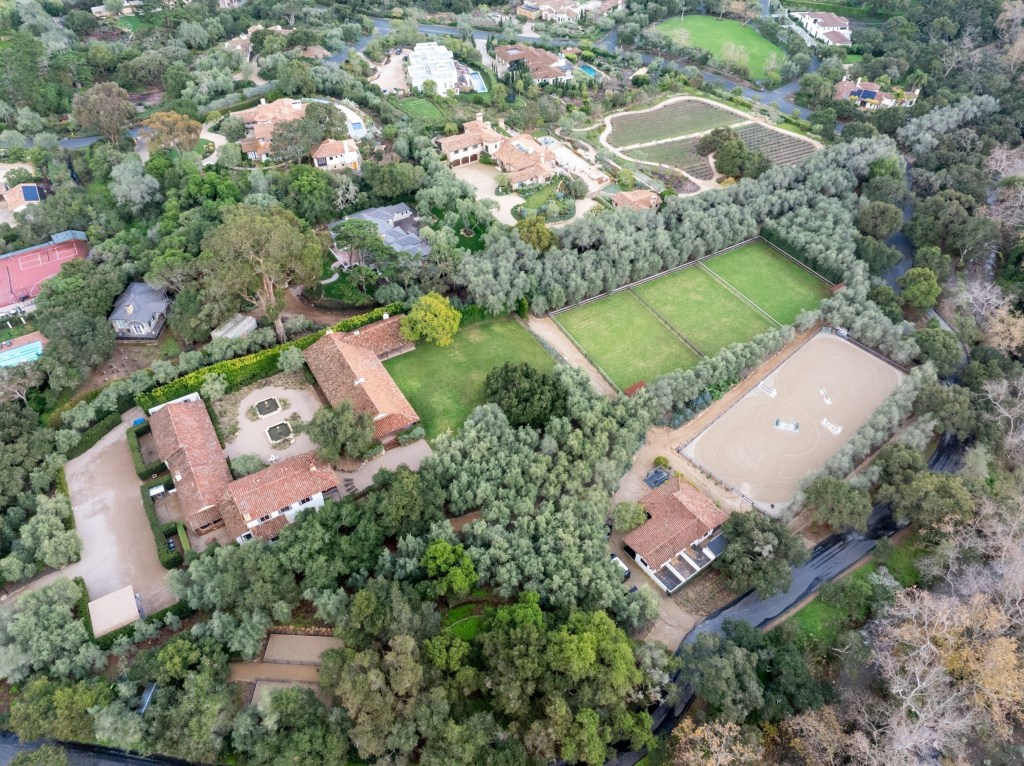 Aerial view of Kendall Jenner's Montecito estate showing multiple houses, horse stables, riding arena, and training facilities surrounded by trees.