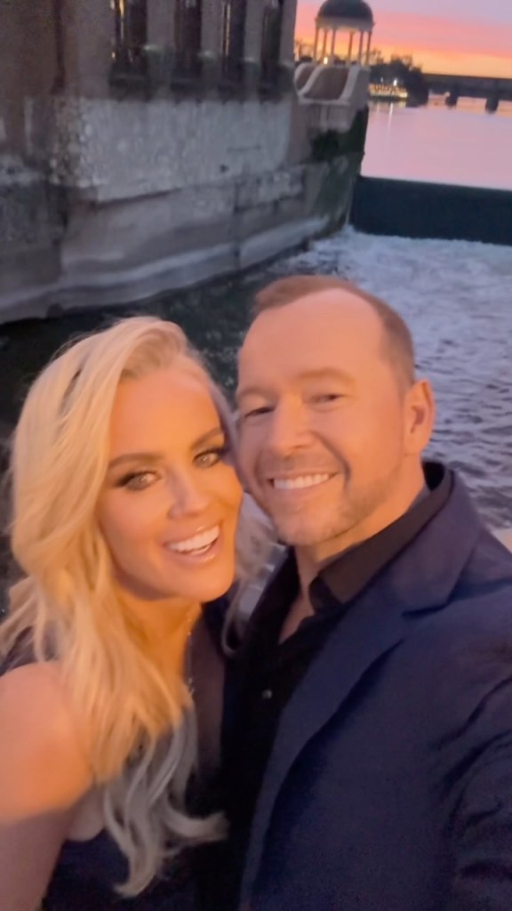 Jenny McCarthy and Donnie Wahlberg posing for a selfie in front of the Hotel Baker at sunset.
