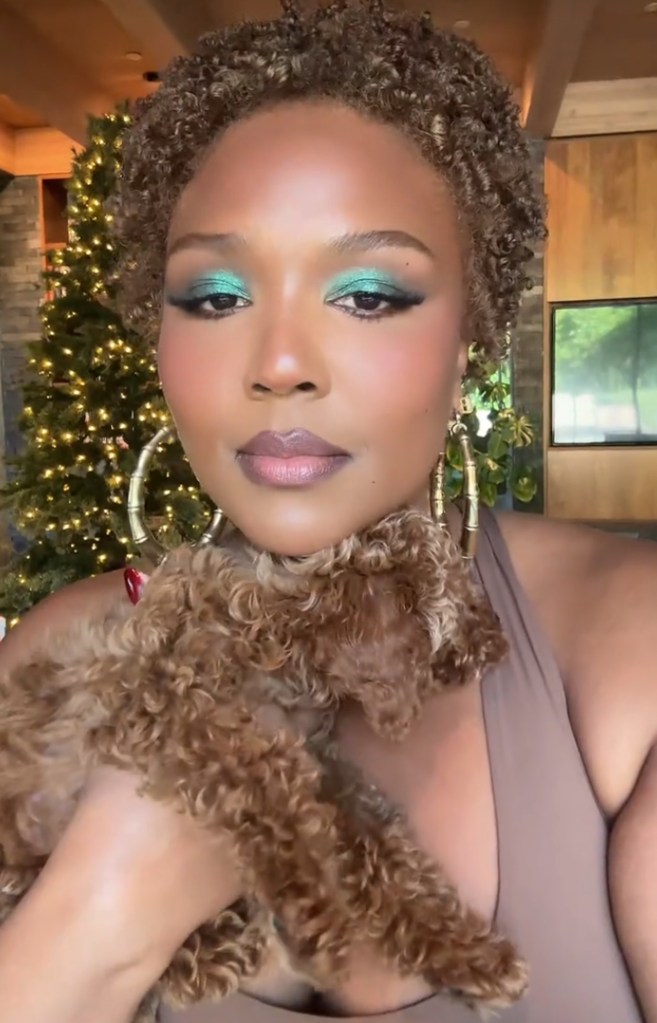 Lizzo debuts short brown curls on TikTok, twinning with her dog and wearing bold green eyeshadow.