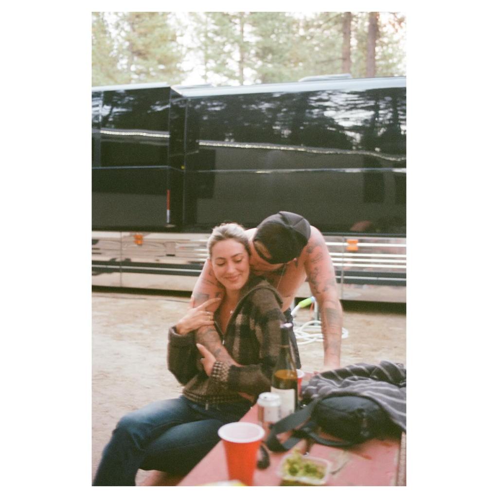 Zach Bryan and Samantha Leonard embracing; she sits with her arms around him.