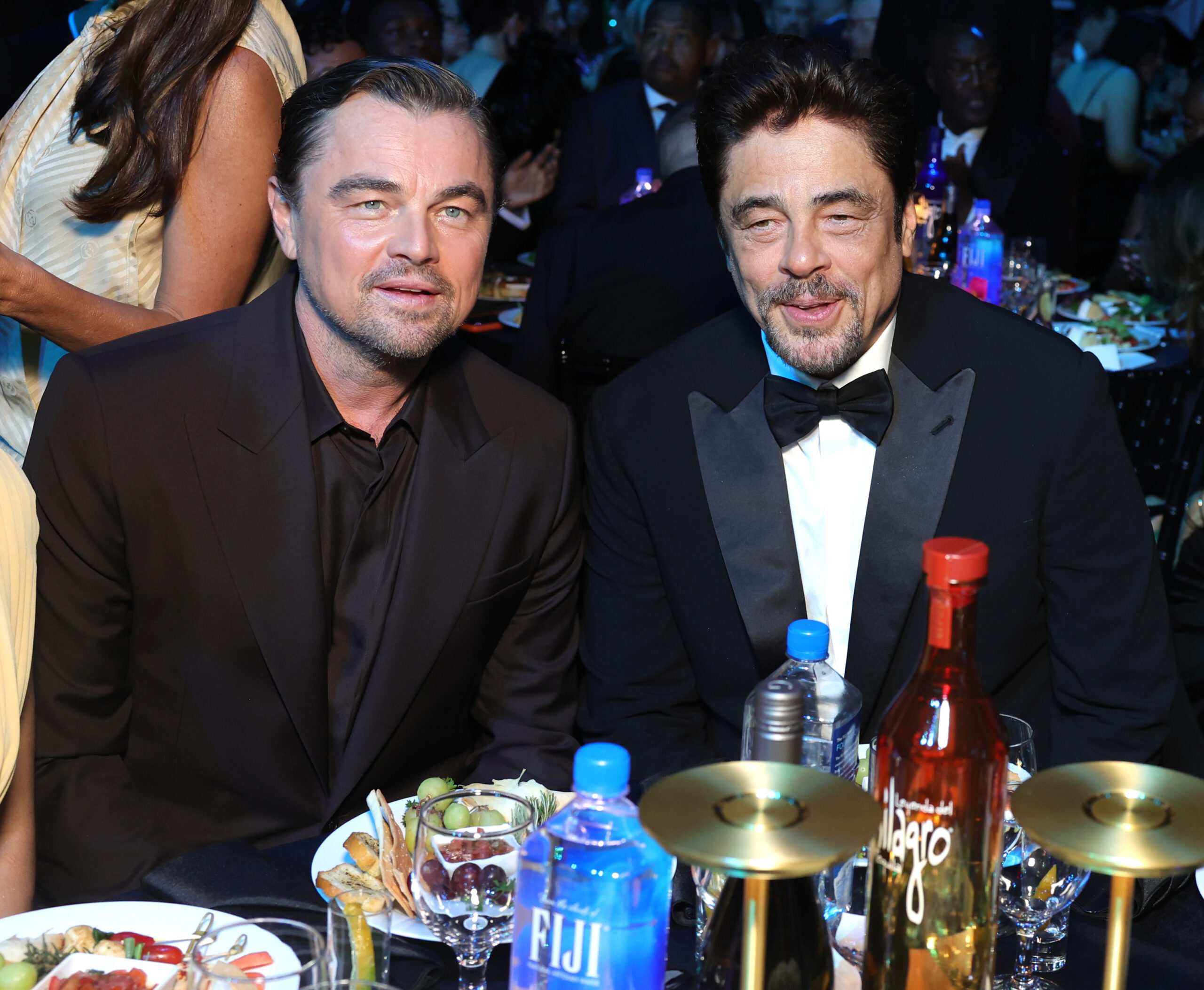 Leonardo DiCaprio and Benicio del Toro pose at their table during the 2026 Critics Choice Awards